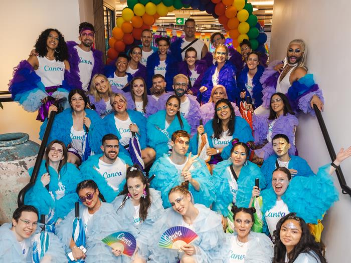 A group of people sitting on stairs posing for the photo. Dressed in bright coloured costumed for Mardi Gras in Sydney