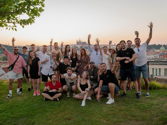 Smart Mockups team at Canva on a hill overlooking Prague posing for a photo, waving their arms in the air