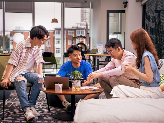 Group of people in our China office working together on a table with a laptop.