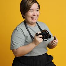 Women sitting on a chair holding a camera and smiling