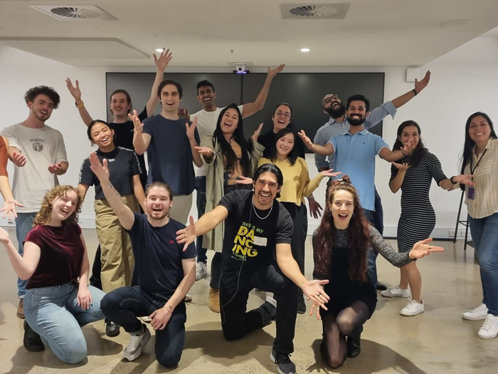 Group of people kneeling down, smiling with their hands up in the air
