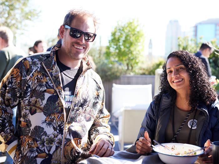 Man and women on the rooftop in the Sydney office eating lunch and smiling to the camera