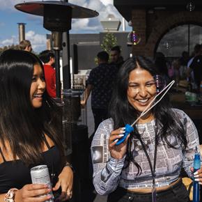 Two women playing with bubbles on Canva rooftop in Sydney
