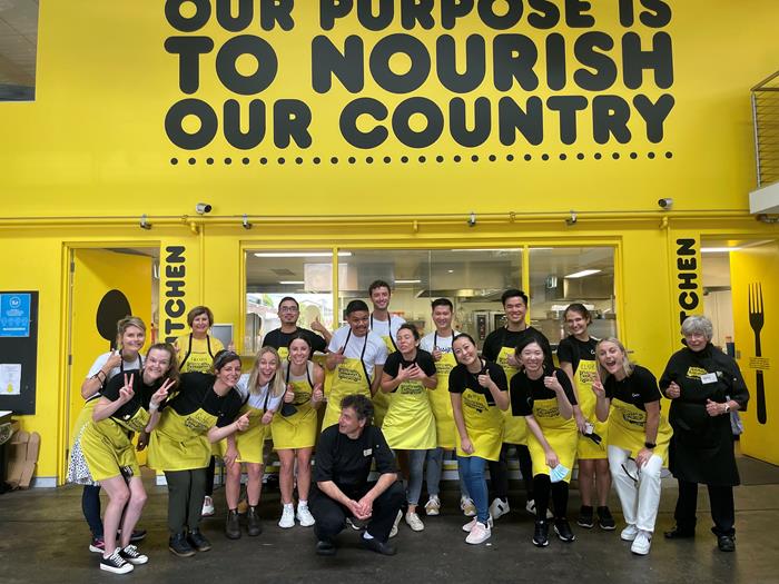 A group of people wearing yellow aprons and volunteering together for OzHarvest in Sydney