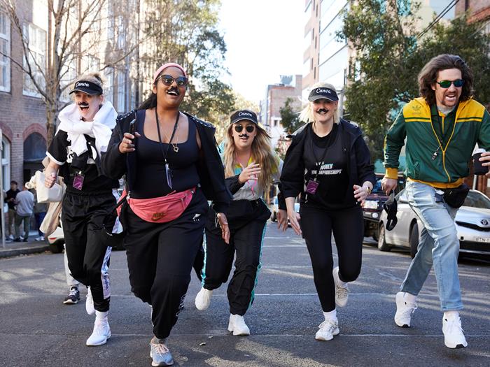 A group of Canva colleagues running i[ the kill dressed in active wear and moustaches