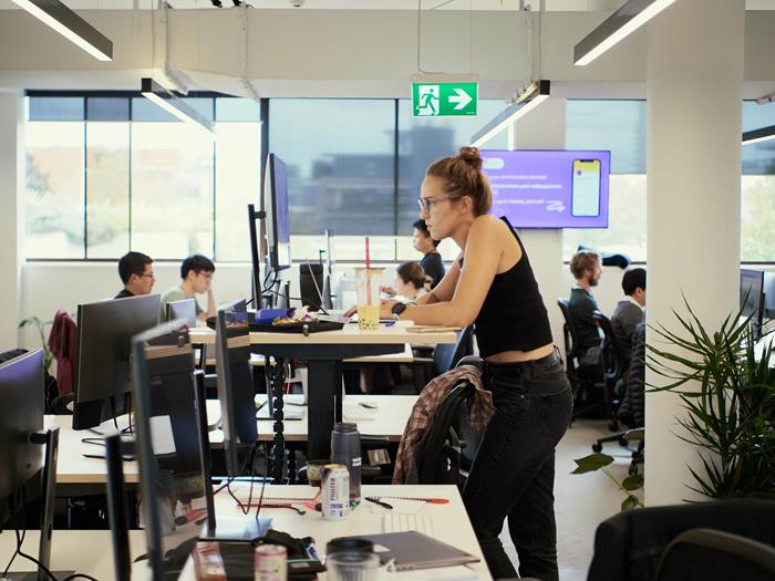 Women standing at her desk working on her laptop