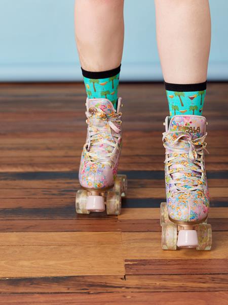 Persons feet in roller blades on the floorboards of a house.