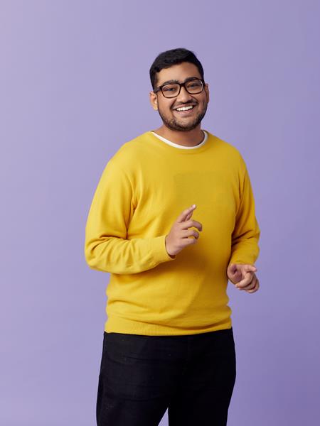 Man in yellow jumper smiling and pointing