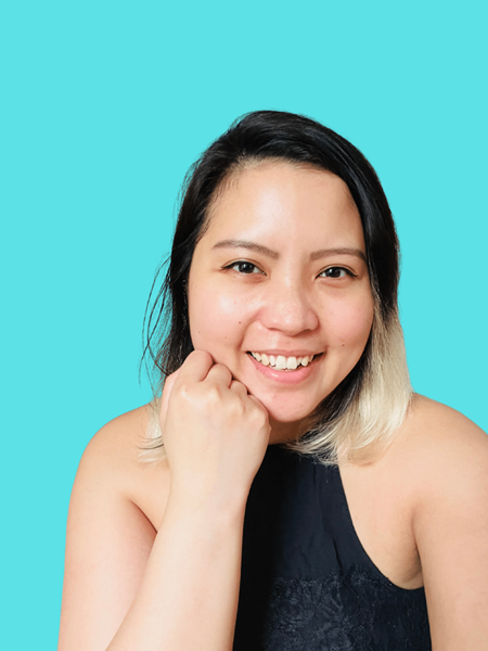 Light skinned woman in a black top resting her chin on her hand.