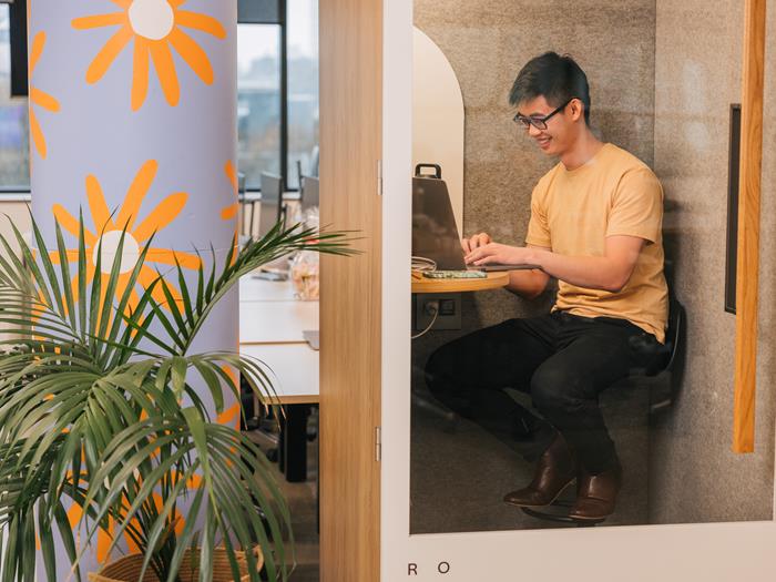 Man in a meeting booth on his laptop