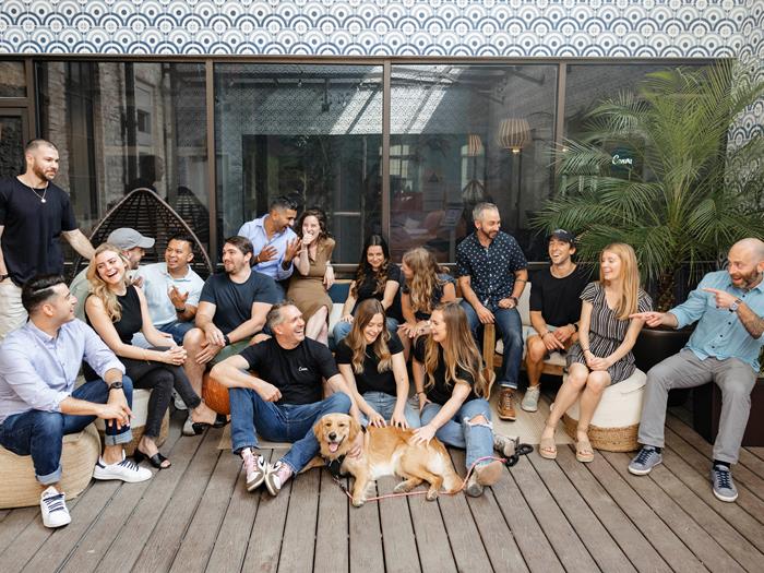 Austin team at the office sitting on the ground posing for a photo and laughing. Two people also patting the office dog.