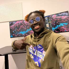 Man point at his Canva hoodie with a colour computer screen in the background