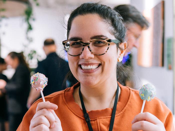 Women wearing an orange jumper smiling at the camera and holding two ice creams