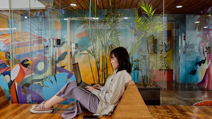 Women sitting on a bench seat in the Manila office working on her laptop