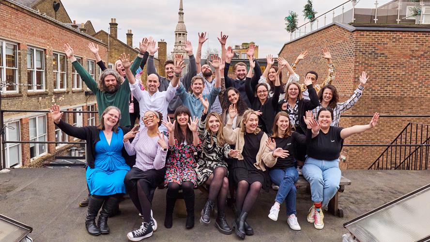 Flourish Office Canva (group of people from Canva with their hands in their air smiling at the camera)