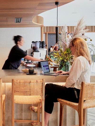 Canva's cafe in the Sydney office. Two colleagues working at the bench top and one is making coffee.