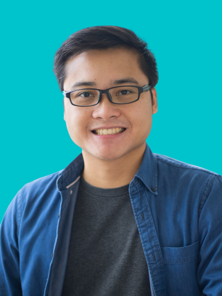 Medium skinned man wearing glasses, a black t shirt and blue shirt, smiling.