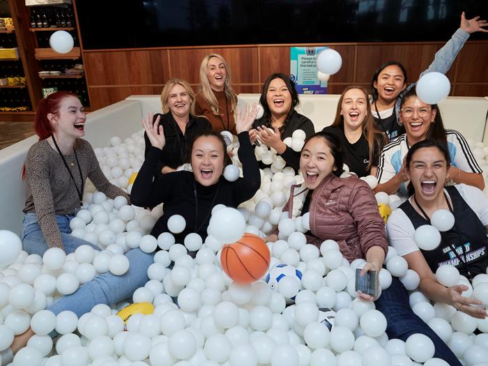 Group of women playing in a ball pit, throwing the balls in the year and laughing