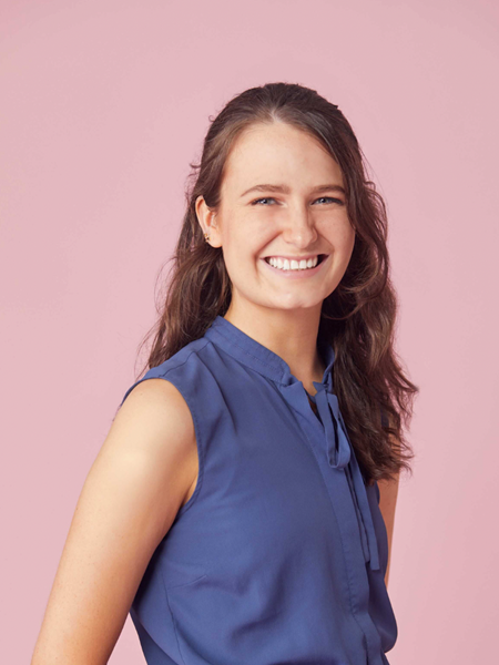 Women with long brown hair wearing a blue dress smiling to the camera