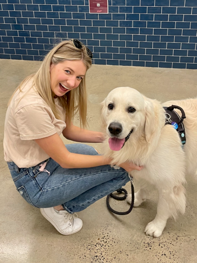 Women bending down to pat her Golden Retriever dog and smiling to the camera