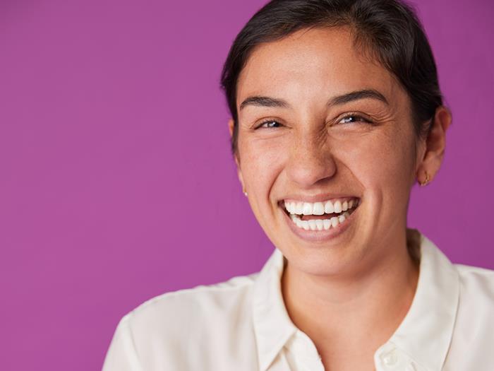 Women with brown hair and white shirt smiling to the camera