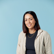Woman smiling at camera wearing black tee and beige shirt