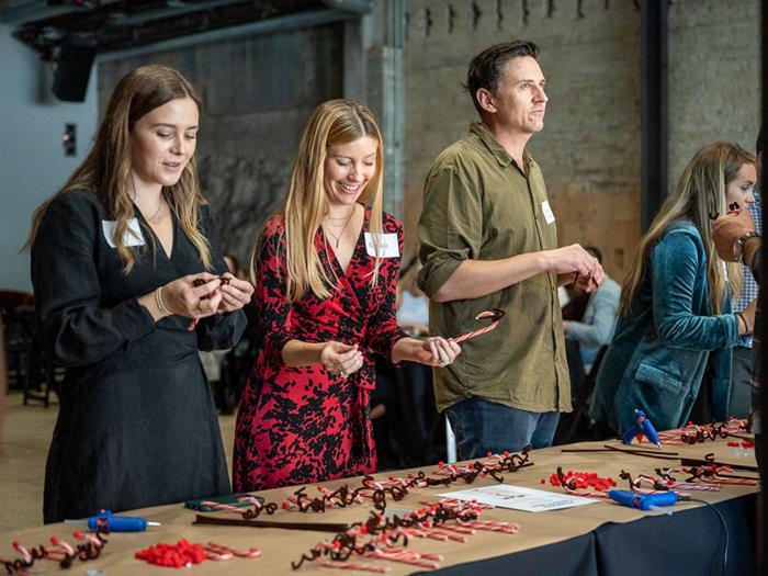 Three people who work at Canva standing in front of a table making Christmas decorations