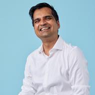 Medium skinned man wearing a white shirt, smiling.