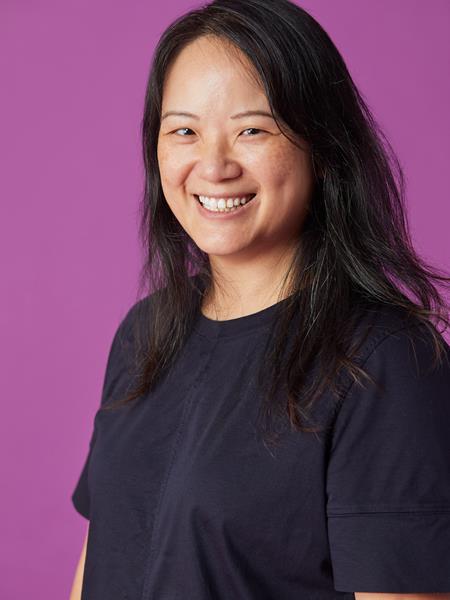 Women in a black t-shirt with long black hair smiling to the camera