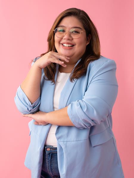 Medium skinned woman in clear framed glasses, blue blazer and white top.