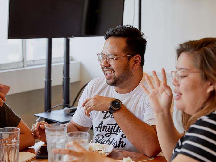 Colleagues sitting at desk in the office laughing together