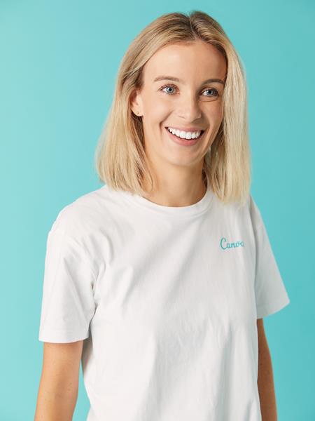 Woman in white Canva t-shirt smiling away from camera