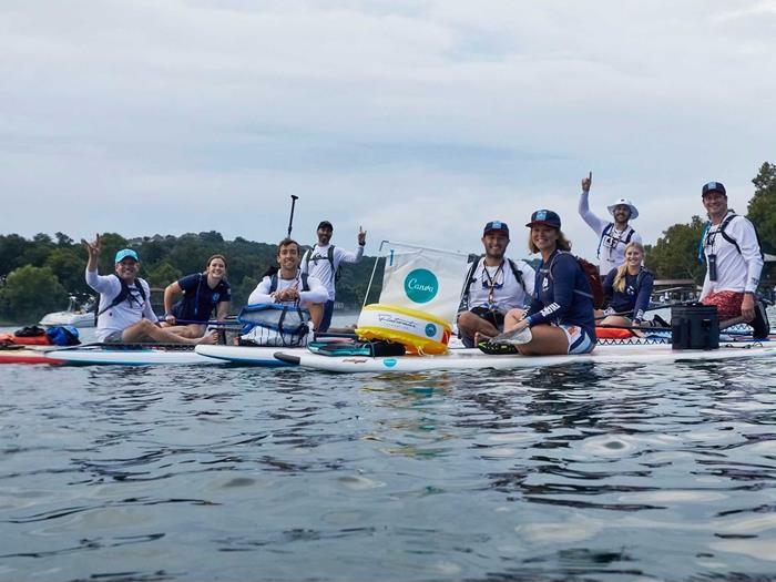 Team in Austin out on the river sitting on stand up paddle boards with a Canva sign